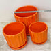 Three orange ceramic planters in different sizes