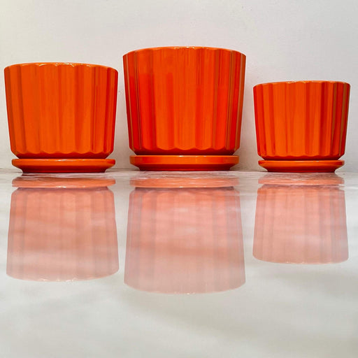 Set of orange ribbed ceramic pots with matching saucers