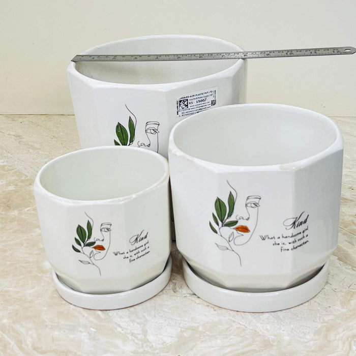 Set of white ceramic planters with line art and matching saucers